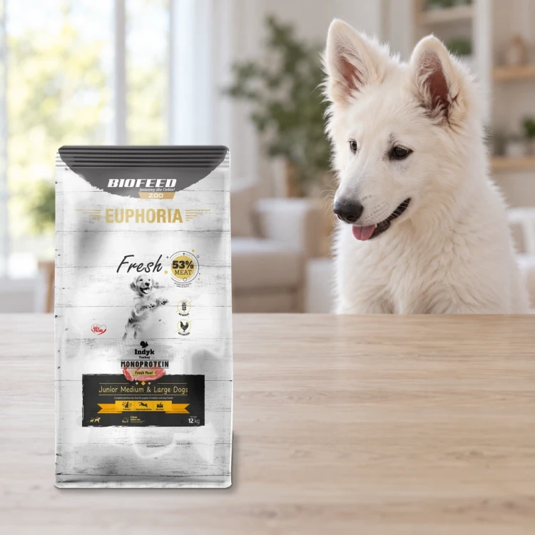 Worek 12 kg karmy Euphoria Fresh z indykiem dla szczeniąt średnich i dużych ras obok szczeniaka w mieszkaniu.
