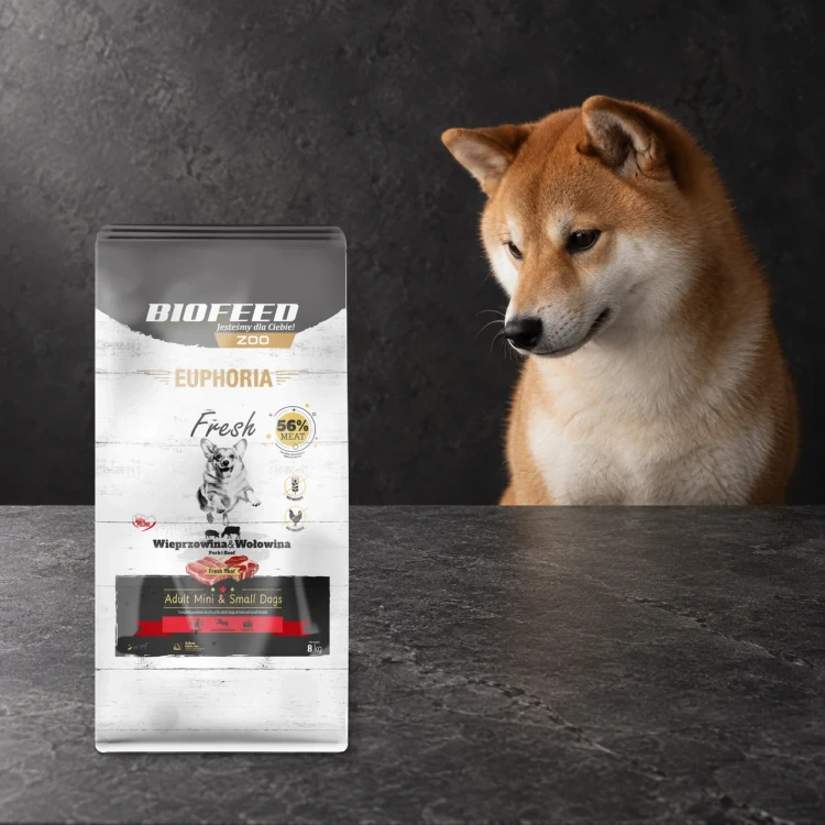 Worek 8 kg karmy Euphoria Fresh z wieprzowiną i wołowiną dla dorosłych psów mini i małych ras obok psa na ciemnym tle.