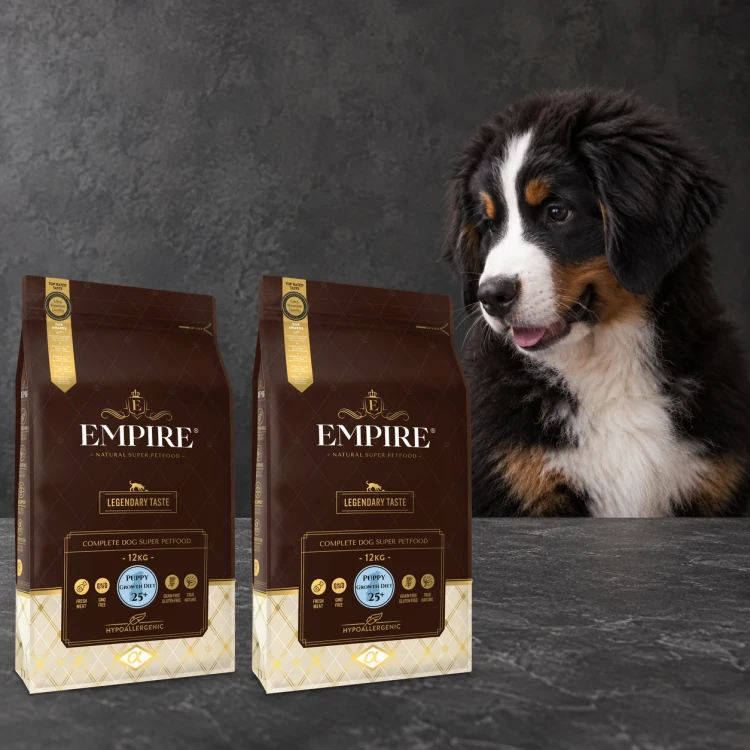 Dwa worki karmy EMPIRE Legendary Taste Puppy Growth Diet 25+ dla szczeniąt dużych ras po 12 kg obok szczeniaka berneńskiego psa pasterskiego na ciemnym tle