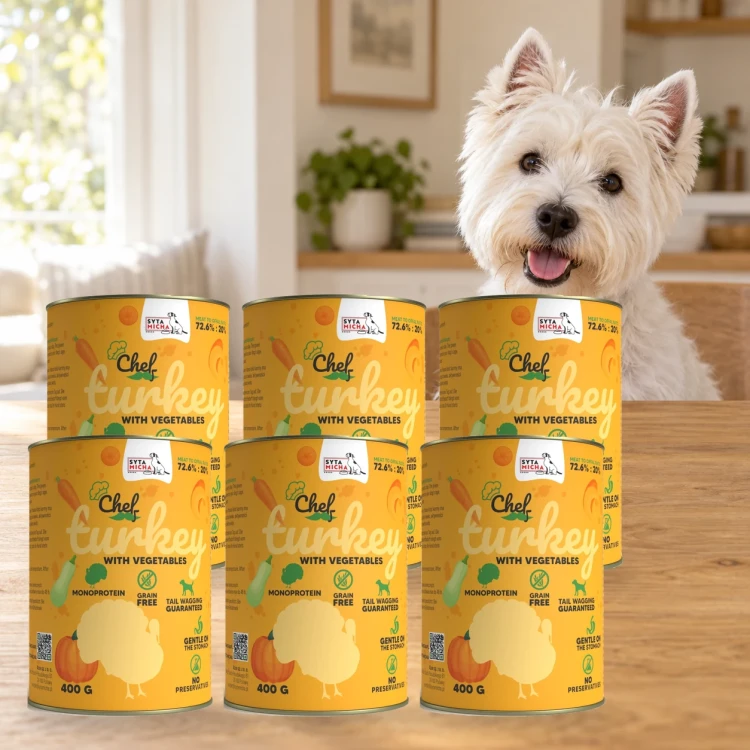 Sześć puszek karmy Syta Micha Indyk z warzywami 6 × 400 g obok psa rasy West Highland white terrier w mieszkaniu