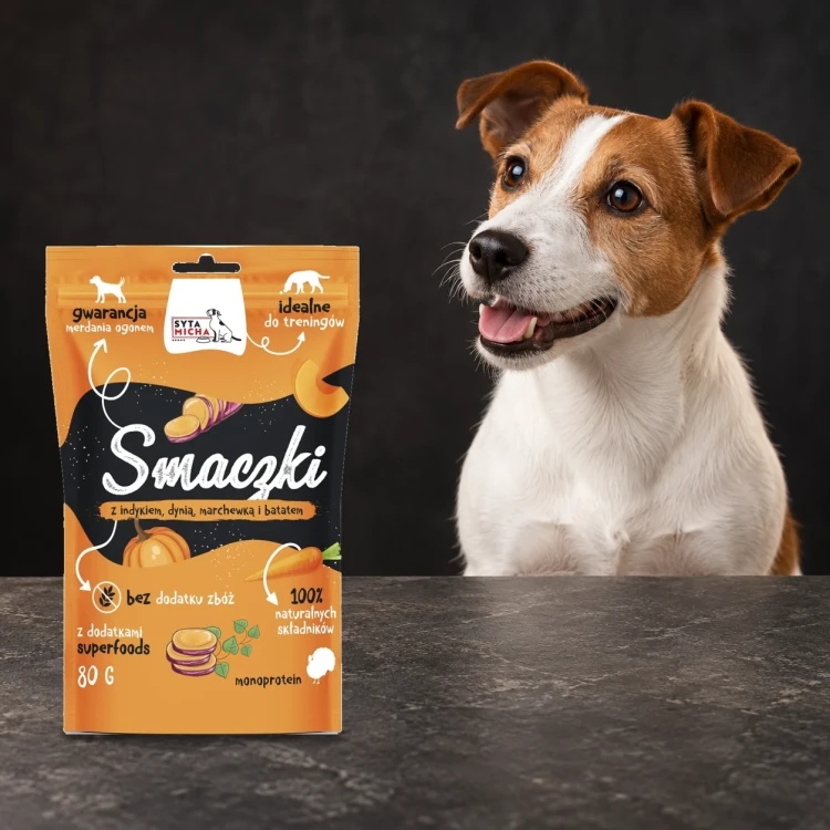 Smaczki Syta Micha z indykiem, dynią, marchewką i batatem 80 g obok psa