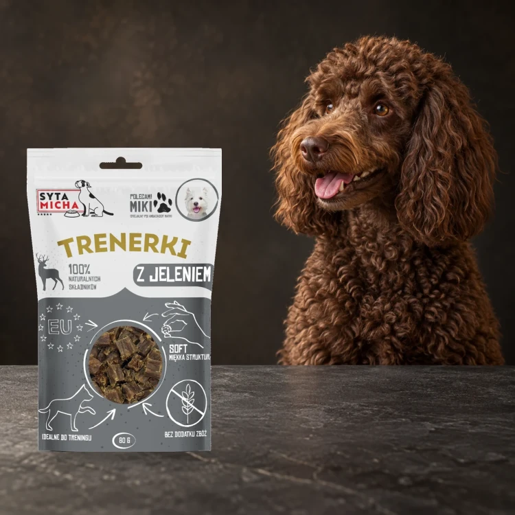 Trenerki Syta Micha z jeleniem 80 g obok psa na ciemnym tle.